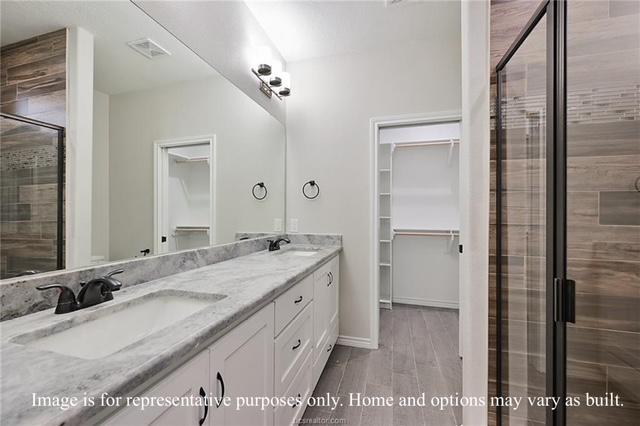 bathroom featuring a spacious closet, wood finished floors, visible vents, and a sink