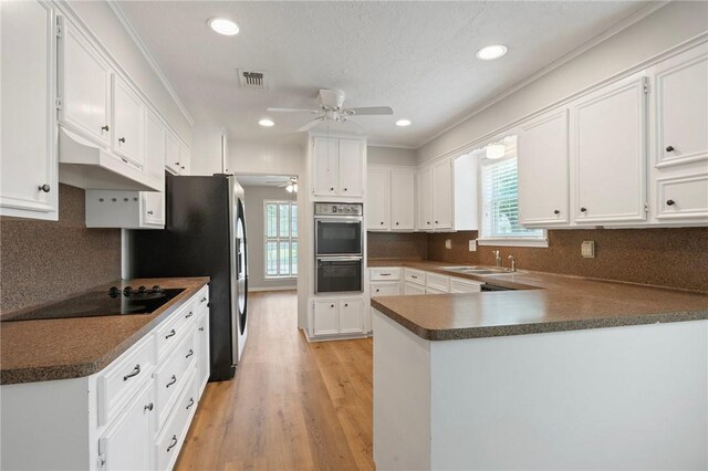 2909 River Oaks Cir, Bryan, TX 77802 - kitchen featuring ceiling fan, black appliances, a peninsula, light wood finished floors, and white cabinets