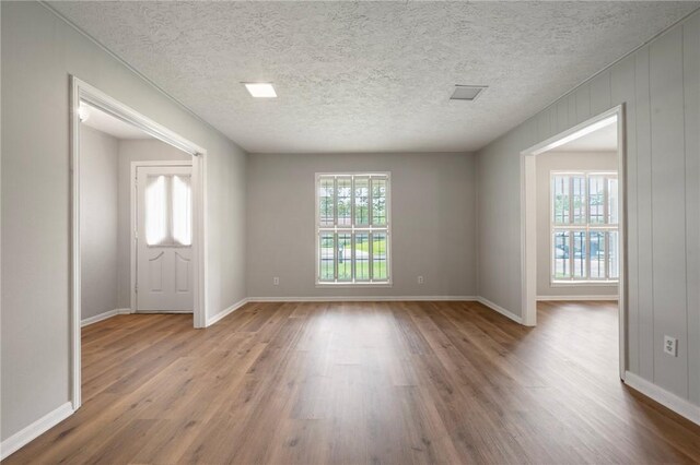 2909 River Oaks Cir, Bryan, TX 77802 - unfurnished room with wood finished floors, plenty of natural light, baseboards, and a textured ceiling