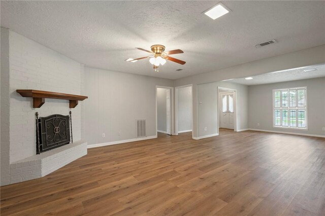 2909 River Oaks Cir, Bryan, TX 77802 - unfurnished living room with wood finished floors, ceiling fan, baseboards, a textured ceiling, and a fireplace