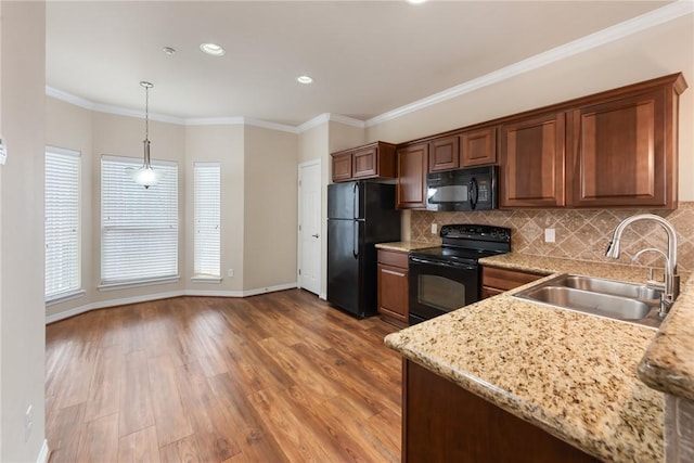 kitchen with sink, backsplash, hanging light fixtures, black appliances, and light hardwood / wood-style floors