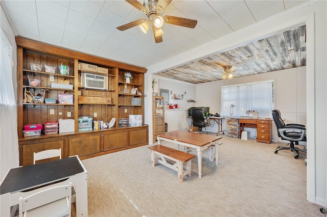 home office featuring a wall unit AC, ceiling fan, beamed ceiling, and light colored carpet