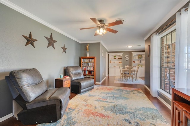 living area featuring dark wood-type flooring, ceiling fan, plenty of natural light, built in features, and ornamental molding