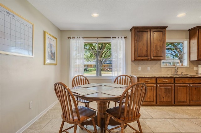 dining area featuring sink, a textured ceiling, and light tile patterned floors