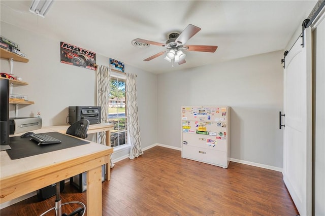 office area featuring ceiling fan, a barn door, and dark hardwood / wood-style floors