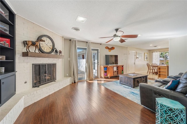 living room with a fireplace, a textured ceiling, ceiling fan, and hardwood / wood-style floors