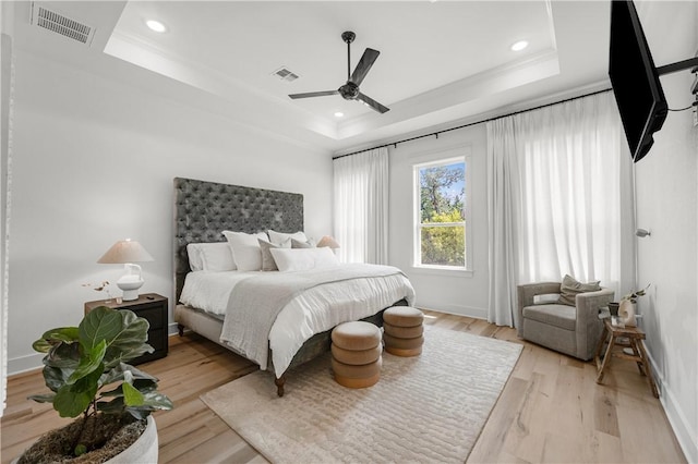 bedroom featuring ceiling fan, ornamental molding, a raised ceiling, and light hardwood / wood-style flooring