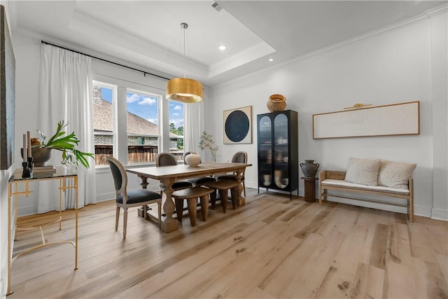 dining area featuring ornamental molding, light hardwood / wood-style flooring, and a tray ceiling