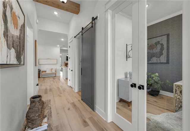 hallway featuring french doors, crown molding, light hardwood / wood-style flooring, beamed ceiling, and a barn door