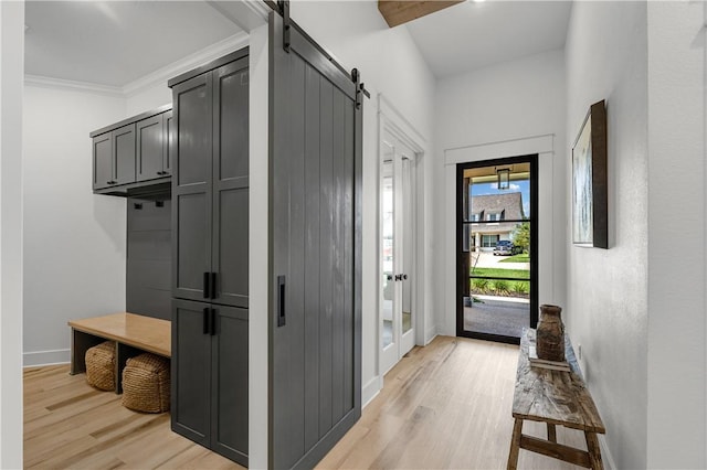 mudroom featuring crown molding, a barn door, and light hardwood / wood-style floors