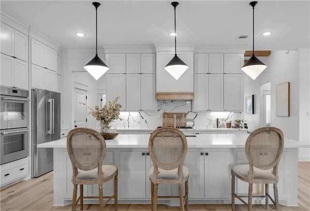 kitchen featuring pendant lighting, stainless steel appliances, white cabinets, and a kitchen island