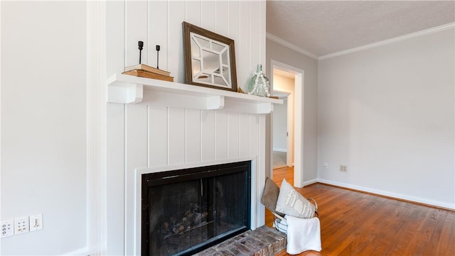 1002 Edgewood Dr, Bryan, TX 77802 - detailed view of wood finished floors, ornamental molding, a brick fireplace, baseboards, and a textured ceiling