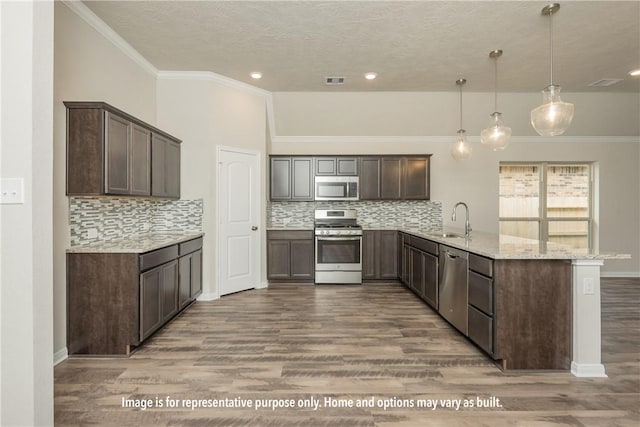 kitchen with kitchen peninsula, stainless steel appliances, decorative light fixtures, and wood-type flooring