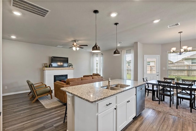 kitchen with white cabinetry, light stone counters, dark hardwood / wood-style flooring, stainless steel dishwasher, and a center island with sink