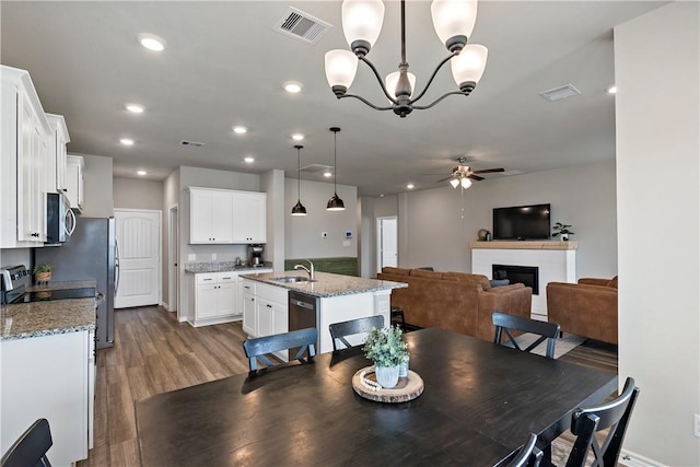 dining space featuring ceiling fan with notable chandelier and wood-type flooring