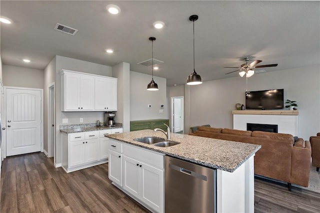 kitchen with stainless steel dishwasher, white cabinets, and an island with sink