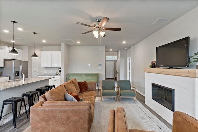 living room featuring ceiling fan, light wood-type flooring, and sink