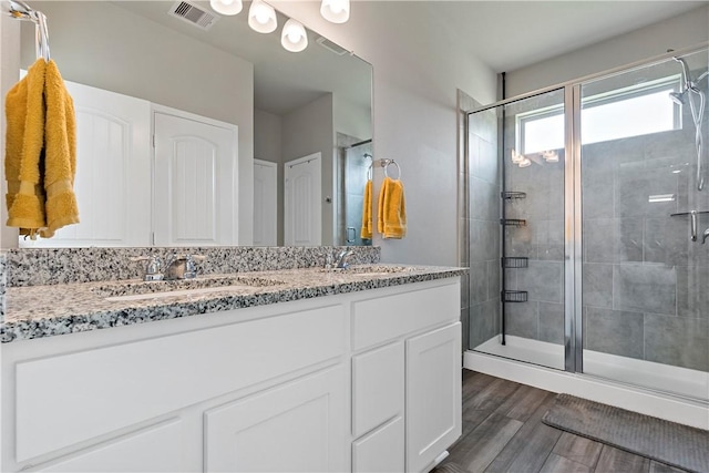 bathroom with hardwood / wood-style floors, vanity, and an enclosed shower