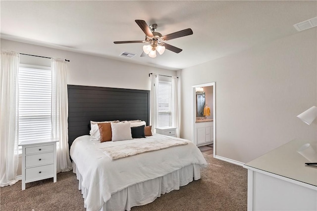 carpeted bedroom with connected bathroom, multiple windows, and ceiling fan