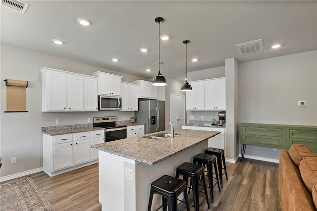 kitchen featuring stainless steel appliances, sink, hardwood / wood-style flooring, a center island with sink, and white cabinets