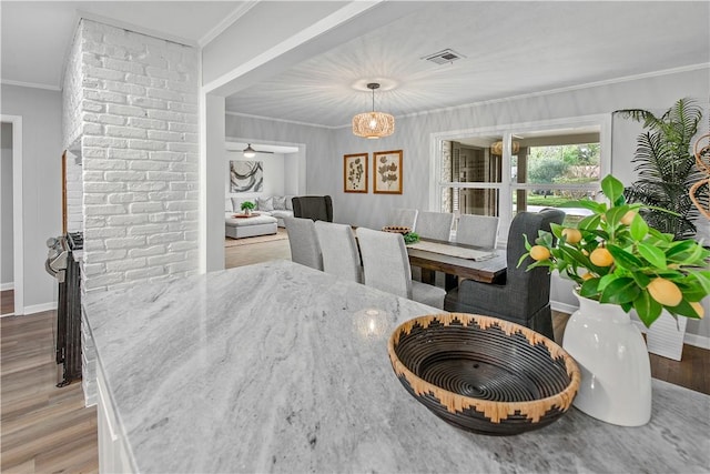 dining area with crown molding and light hardwood / wood-style flooring