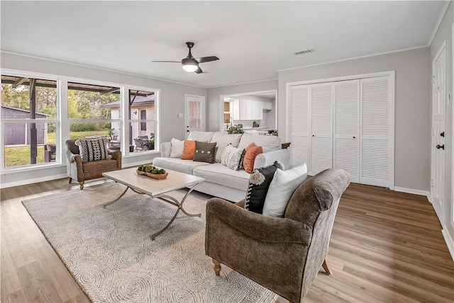 living room featuring light wood-type flooring, ceiling fan, and ornamental molding