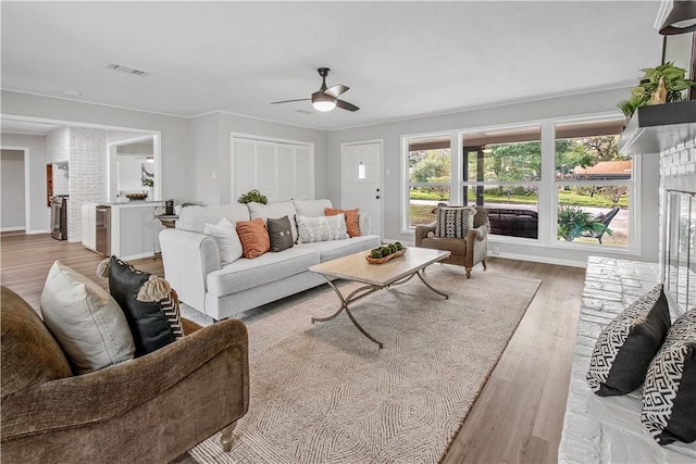 living room with ceiling fan, light wood-type flooring, and ornamental molding