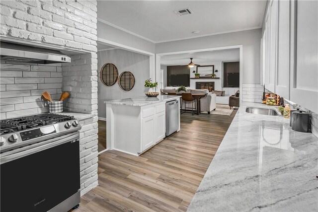 kitchen featuring light stone countertops, white cabinets, light hardwood / wood-style floors, and appliances with stainless steel finishes