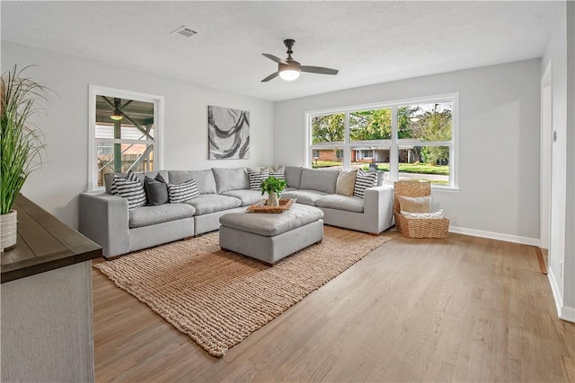 living room featuring a textured ceiling, light hardwood / wood-style flooring, a wealth of natural light, and ceiling fan