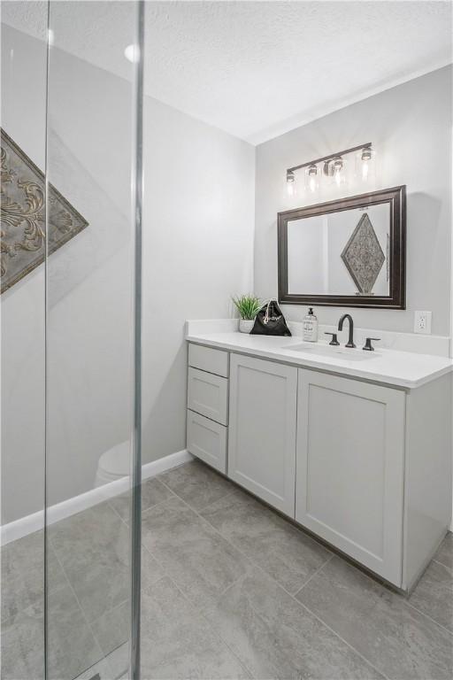 bathroom featuring tile patterned flooring, a textured ceiling, vanity, and toilet