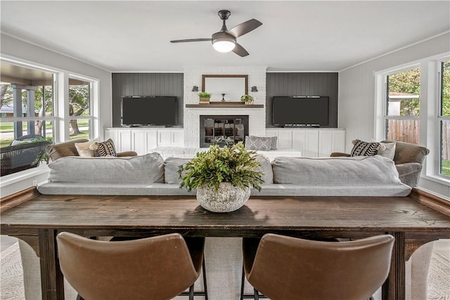 living room featuring a large fireplace, a wealth of natural light, ornamental molding, and ceiling fan