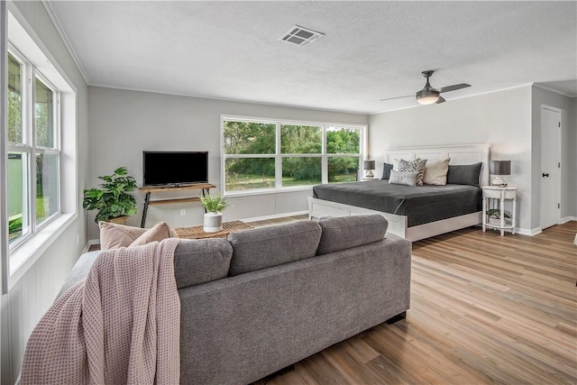 bedroom featuring a textured ceiling, ceiling fan, wood-type flooring, and ornamental molding