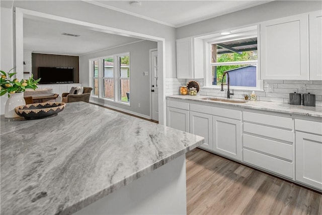 kitchen featuring backsplash, white cabinetry, sink, and light stone countertops