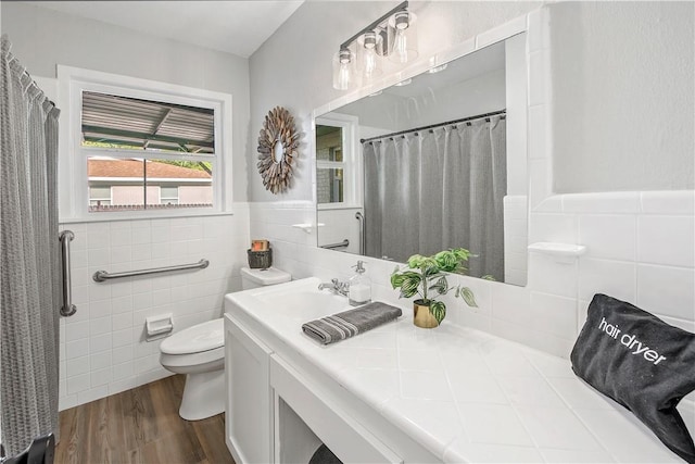 bathroom with vanity, toilet, wood-type flooring, and tile walls