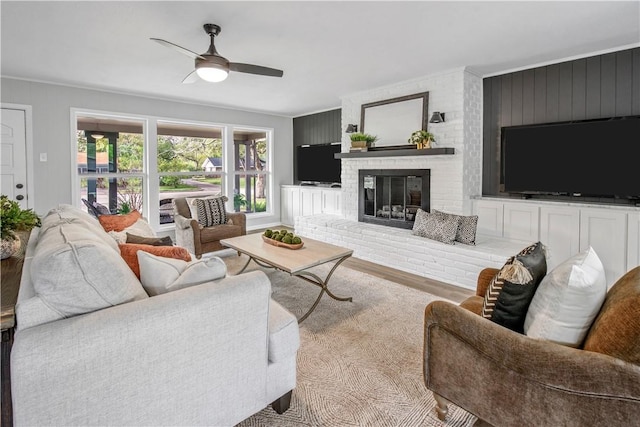 living room with ceiling fan, light hardwood / wood-style flooring, and a brick fireplace