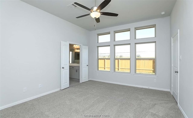 unfurnished bedroom with light carpet, ensuite bathroom, and ceiling fan