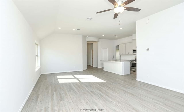 unfurnished living room with lofted ceiling, ceiling fan, light wood-type flooring, and sink