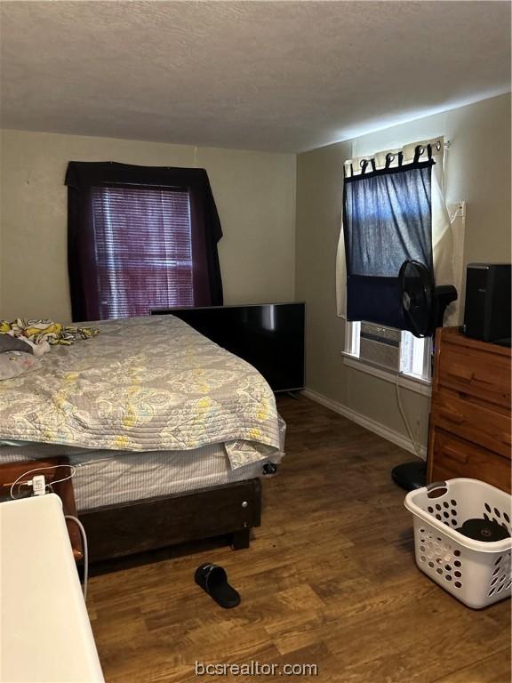 bedroom with wood-type flooring, a textured ceiling, and cooling unit