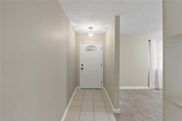 doorway with light tile patterned floors, baseboards, a textured ceiling, and light colored carpet