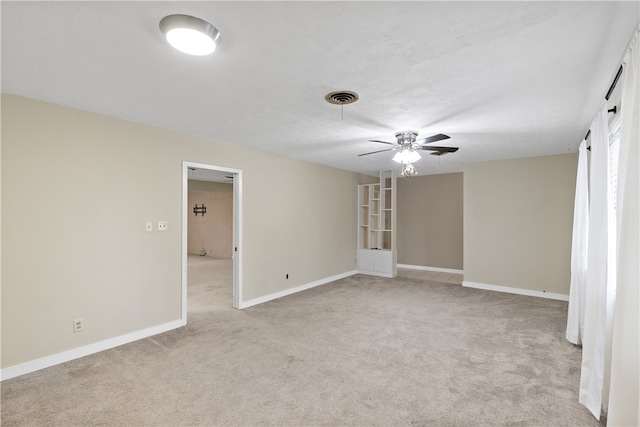 spare room featuring baseboards, a ceiling fan, visible vents, and light colored carpet