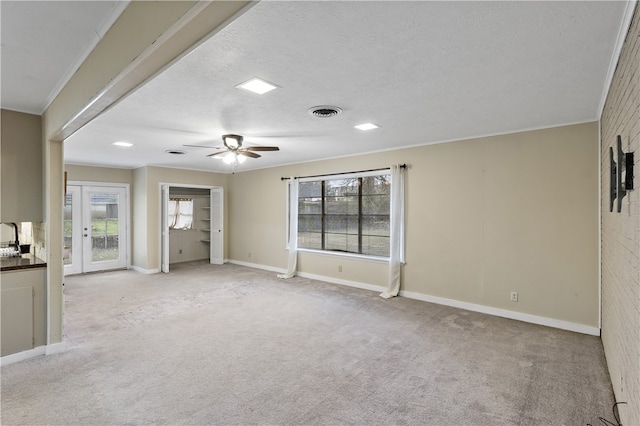 interior space featuring visible vents, ornamental molding, light carpet, a textured ceiling, and baseboards