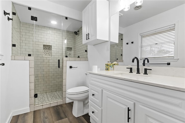 full bathroom featuring vanity, wood finished floors, toilet, and a shower stall