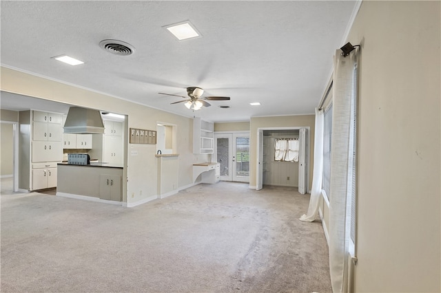 unfurnished living room with ceiling fan, a textured ceiling, light carpet, visible vents, and baseboards