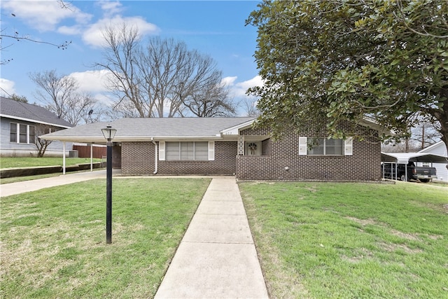 view of front of home with a front lawn, an attached carport, and brick siding