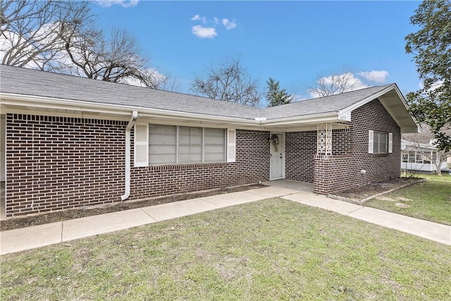 ranch-style house with brick siding, a front lawn, and roof with shingles