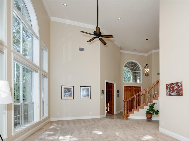 unfurnished living room featuring plenty of natural light, a towering ceiling, and ornamental molding