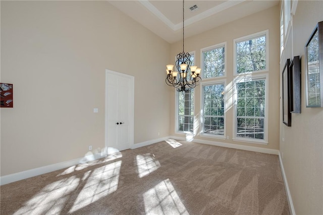 unfurnished dining area featuring a high ceiling, carpet floors, and a notable chandelier