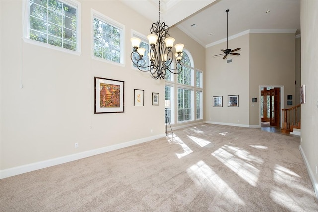 interior space with a high ceiling, ceiling fan with notable chandelier, light colored carpet, and crown molding