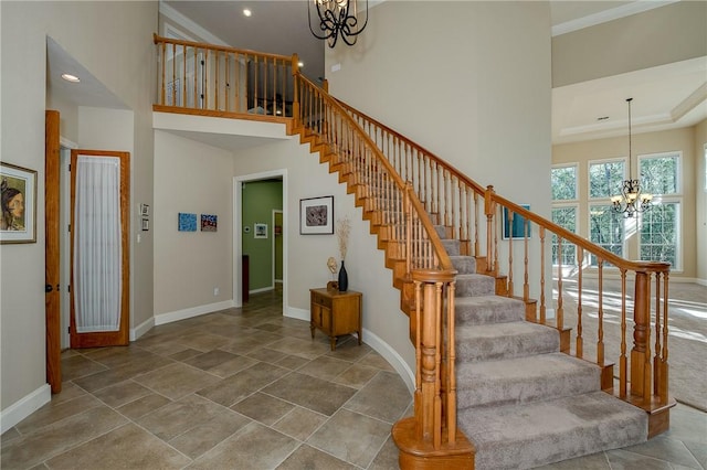 staircase with ornamental molding, a high ceiling, and an inviting chandelier