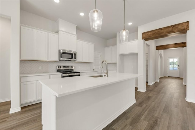 kitchen with white cabinets, appliances with stainless steel finishes, an island with sink, and sink